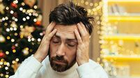 A man has a headache for Christmas, a close-up photo on New Year's Eve near the tree, a man holding his head with his hands, sic
