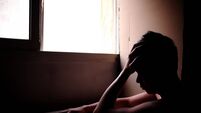 Sillhouette of a sad and problematic young man sitting next to a window light source. Mental health concept