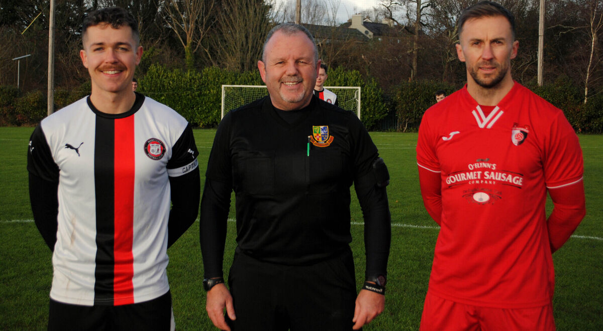 City Wanderers captain Eric Marah (right) with Moneygall's Jack O'Brien, accompanied by referee Paul O'Sullivan.