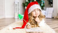 Little girl in Santa hat writes letter to Santa Claus