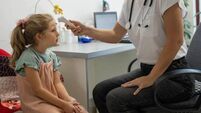 Female doctor is taking a child patient's temperature using a digital thermometer at pediatric office