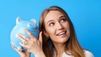 Beautiful smiling young woman with piggy bank on blue background