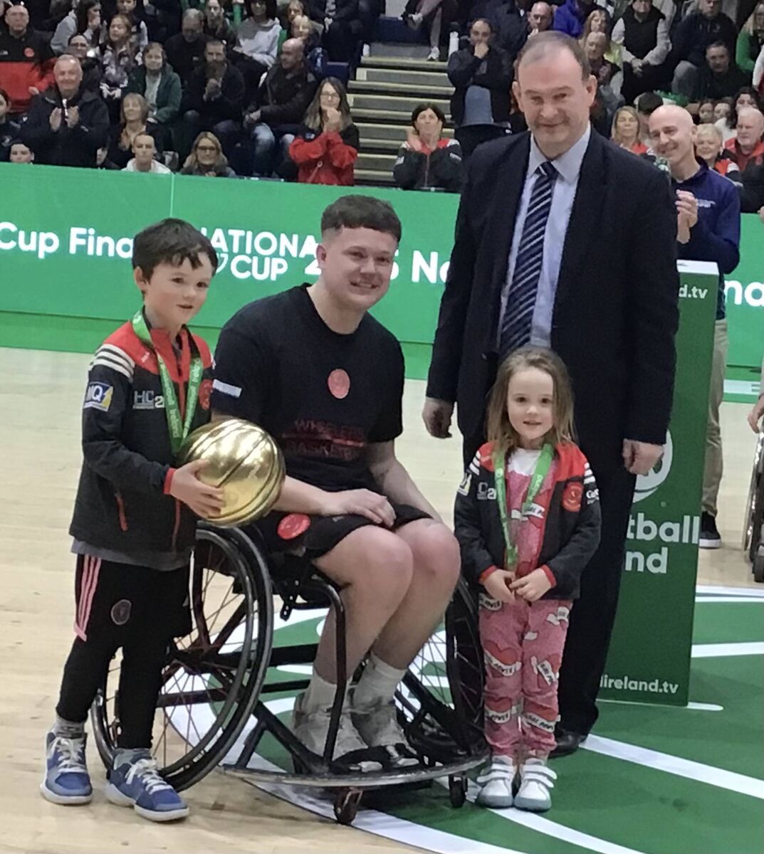 Rebel Wheelers Adam Drummond, the IWA National Cup final MVP for the second year in a row with his niece and nephew Max and Toby Drummond and John Feehan CEO of Basketball Ireland. Rebel Wheelers Adam Drummond, the IWA National Cup final MVP for the second year in a row with his niece and nephew Max and Toby Drummond and John Feehan CEO of Basketball Ireland.