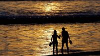 Two tourists walk along Kuta beach durin