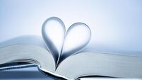book with heart shaped pages over light background