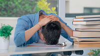 student at desk with stressed or overwhelmed books