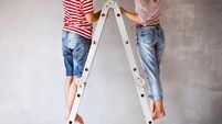 Unrecognizable couple painting walls in their house.