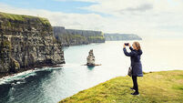Woman tourist taking pictures of cliffs along the coast