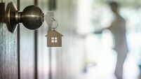 House key with home keyring in keyhole on wood door, copy space