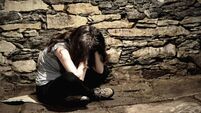 Young breakdown woman sitting on the peace of cartoon in the dark cellar, victim of violence, kidnapping or captive, view throug