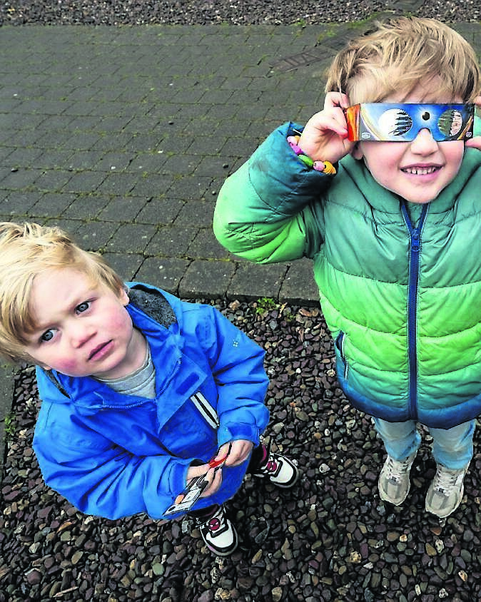 Nicholas Lettau, with his brother Julian, from Shanakiel, adjusts his eclipse glasses as he scans the sky during the partial eclipse at Blackrock Castle Observatory.	Picture: Chani Anderson
                    