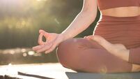 Woman practicing Padmasana on yoga mat on wooden pier near pond, closeup with space for text. Lotus pose