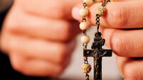 Woman (only close-up of hands to be seen) with rosary sending a prayer to God, the dark setting suggests she is sad or lonely