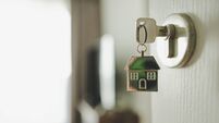 Open the door and door handle with a key and a keychain shaped house. Property investment and house mortgage financial real esta
