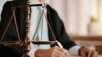 Closeup, scales and law on table, office and attorney man in blurred background with reading for crime analysis. Advocate, lawye