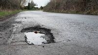 Deep road pothole filled with rainwater.