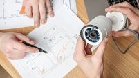 Two people discussing CCTV project. Video security equipment and blueprint on a table