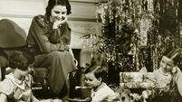 Mother watching three children playing by Christmas tree, (B&W)