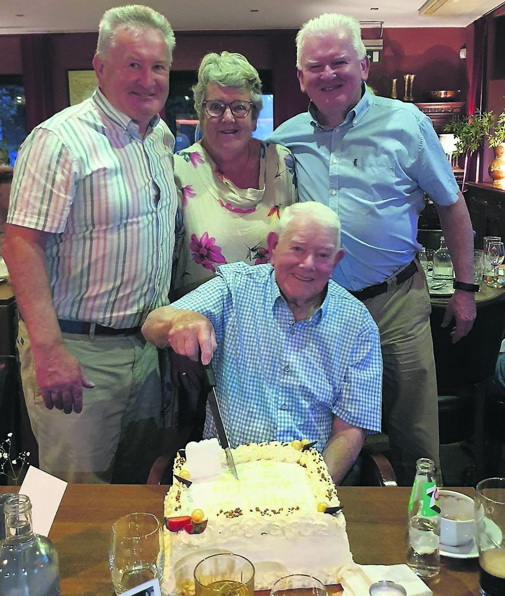 Tom McCarthy cuts the cake for his 100th birthday at a party on Saturday, with his children Denis, Tadgh, and Margaret