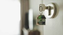 Open the door and door handle with a key and a keychain shaped house. Property investment and house mortgage financial real esta