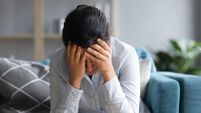 Unhappy depressed Indian woman holding head in hands, sitting alone
