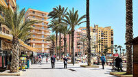 People tourists stroll along seafront promenade of Playa del Cura. Torrevieja, Spain