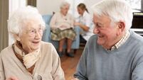 Smiling senior couple eating meal in care home