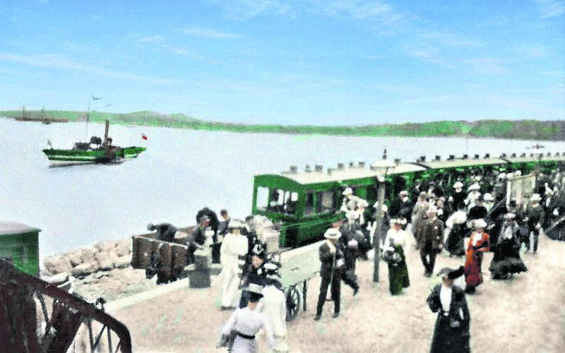 A historic photo, colourised by Joe Healy, of the opening day of the Monkstown to Crosshaven railway station in 1904, with a Cork Harbour river steamer in the background