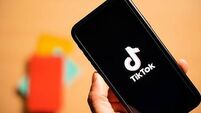 Rome, Italy, 24 January 2021. Overhead shot of a human hand holding a smartphone with the TikTok logo.