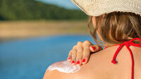 Young woman applying sun lotion on summer vacation