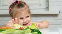 a little girl emotionally pushes away a plate of offered vegetables. children refuse vegetables in favor of junk food