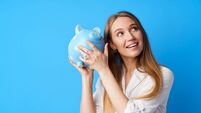 Beautiful smiling young woman with piggy bank on blue background