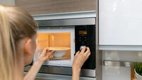 woman warm up the food in microwave oven at home