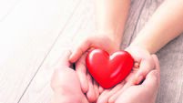 The adult and the child holding red heart.