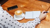 Woman in cafe sitting and writing in notebook