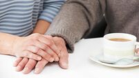 Close Up Of Woman Sharing Cup Of Tea With Elderly Parent