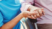Nurse consoling a senior woman in the nursing home holding her hand in the nursing home