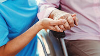 Nurse consoling a senior woman in the nursing home holding her hand in the nursing home