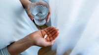Adult woman holding a pill and a glass of water. Female taking medicine. Treating at home. Patient recovering in a hospital. Men