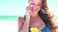 Woman with freckles applying sunscreen on face
