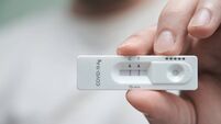Close-up of a hand holding a positive antigen test for COVID-19.