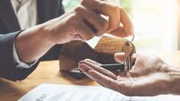 Estate agent giving house keys to customer and sign agreement in office.