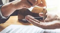 Estate agent giving house keys to customer and sign agreement in office.
