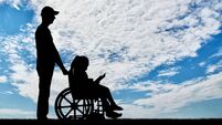 A disabled girl in a wheelchair and her dad on a walk reading a book