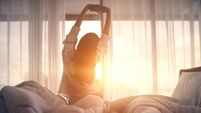 Happy woman stretching in bed after waking up. Happy young girl greets good day.