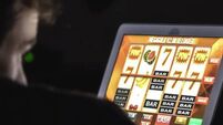 Gambling addicted man with glasses in front of online casino slot machine on laptop computer at night
