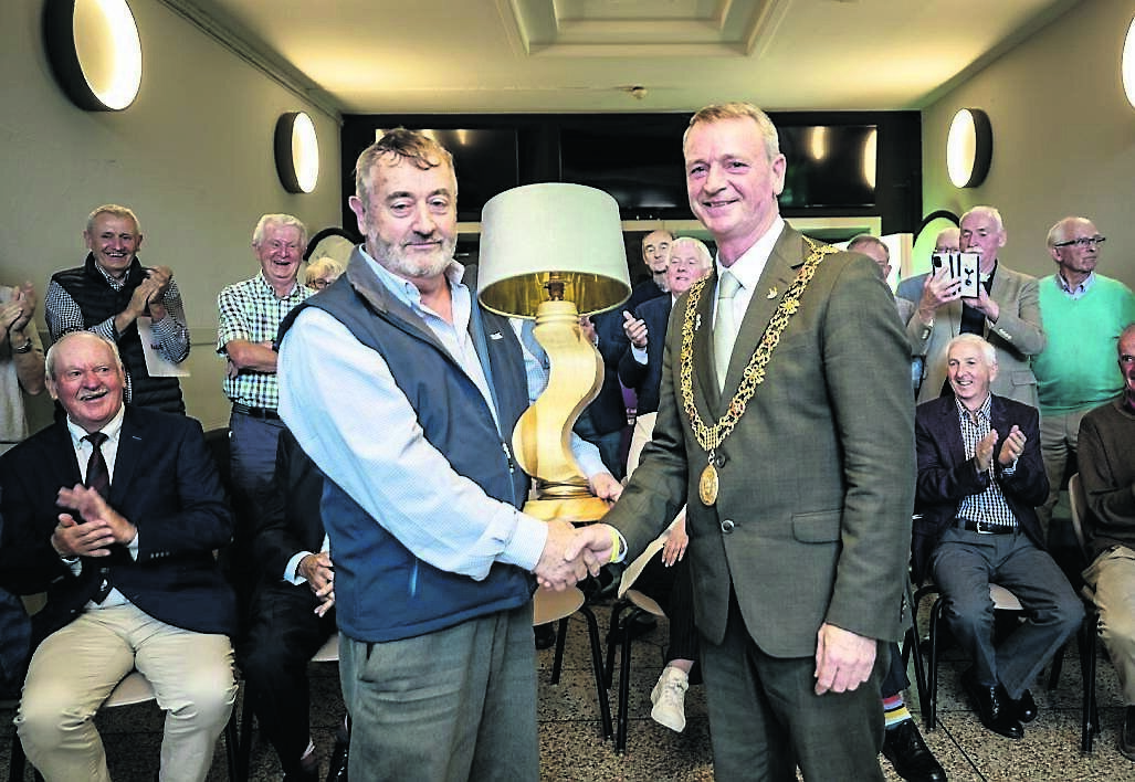 Lord Mayor of Cork, Councillor Fergal Dennehy, is presented with a handmade lamp crafted from a fallen tree by his former woodwork teacher, Michael O’Sullivan, at the reunion event