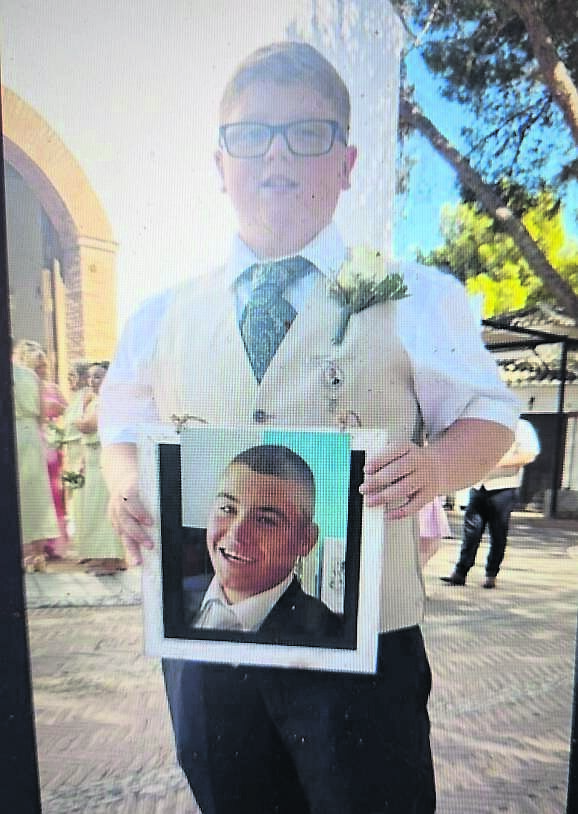 Junior groomsman Jayden holding a photo of his uncle Craig Ring, who was a friend of Clara Kidney and Stephen McNamara