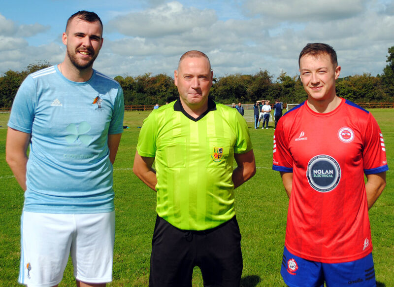 Rathcoole Rovers captain Mark Dennehy (right), with Los Zarcos' Pa Dineen, accompanied by referee Alan McDonagh.