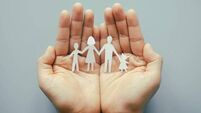 Hand holding family paper cut on blue background. Family day concept, foster care, domestic violence, homeschool, international